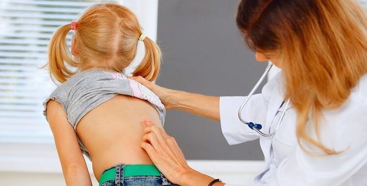 doctor examines the back of a child with lower back pain